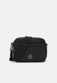 Borsa a tracolla nera realizzata in materiale morbido, con due scomparti con zip e una tracolla. Dettaglio del logo argentato sulla parte anteriore.