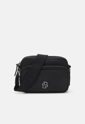 Black crossbody bag made of smooth material, featuring two zippered compartments and a shoulder strap. Silver logo accent on the front.
