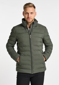 Groene pufferjack met een hoge kraag, voorzien van een volledige rits aan de voorkant en twee zijzakken. Gemaakt van een soepele, lichte stof.