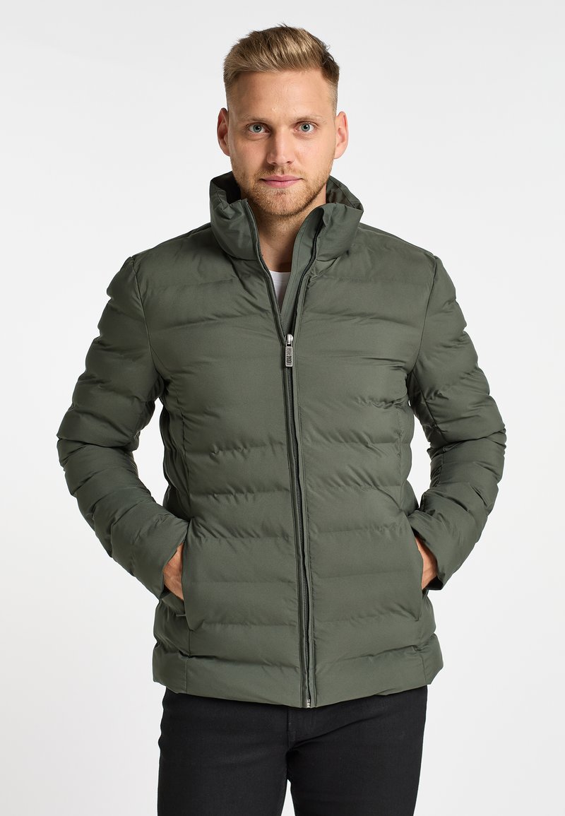 Groene pufferjack met een hoge kraag, voorzien van een volledige rits aan de voorkant en twee zijzakken. Gemaakt van een soepele, lichte stof.