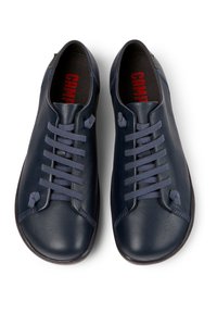 Marineblauwe leren schoenen hebben een ronde vorm met een gladde textuur. Ze hebben zes paar veterogen en platte sluitingen. Rood logo aan de binnenkant.