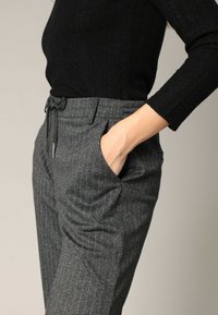 Grijze pinstripe broeken met een op maat gemaakte pasvorm, voorzien van een trekkoord in de taille en zijzakken, gedragen met een zwarte textuur lange mouw top.