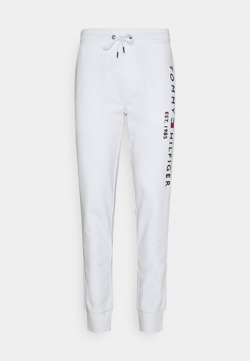 Vita sweatpants med elastisk midjeband och snörning. Har en vertikal "TOMMY HILFIGER"-logotyp och "EST. 1985" i blått på sidan.