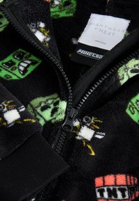 Black fleece nightwear featuring Minecraft motifs, zip closure, ribbed cuffs, and a soft texture with green and white character designs.