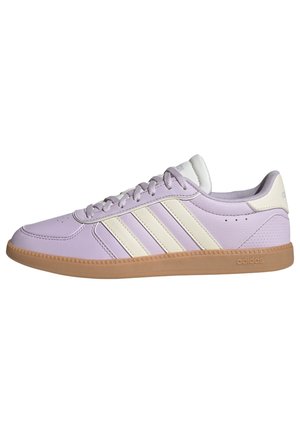 Baskets Adidas lilas avec trois bandes crème, semelle en gomme et lacets, vues de côté sur fond blanc.