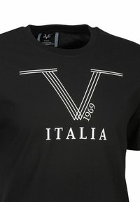 Schwarz Baumwoll-T-Shirt mit einem großen weißen "V"-Design und parallelen Linien sowie dem Text "ITALIA 1969" darunter. Rundhalsausschnitt und kurze Ärmel.