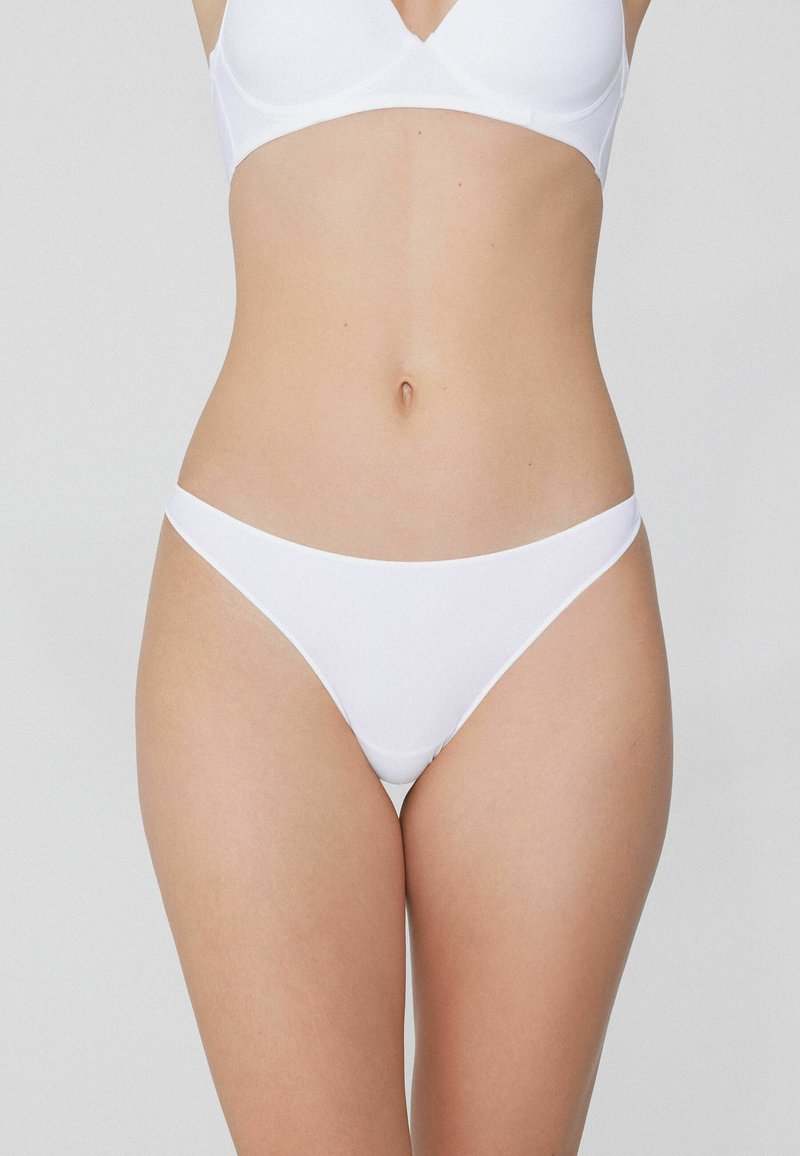 Białe majtki bikini o gładkiej fakturze, niskim kroju i minimalnym zasięgu. Wykonane z elastycznego materiału dla wygody.