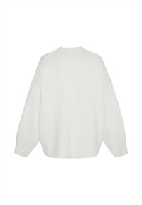 Pull en tricot blanc à coupe ample, épaules tombantes, poignets côtelés et design texturé. Dos uni sans motifs ni accents visibles.