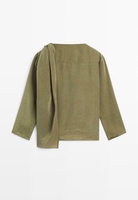 Chemise à manches longues vert olive avec une coupe ample, présentant un accent drapé sur l'épaule et un col rond. Tissu texturé avec un minimum de détails.