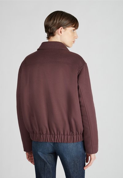 Bordeaux jack met kraag en elastische zoom, met een gladde textuur en een relaxed fit. Gecombineerd met denim jeans.