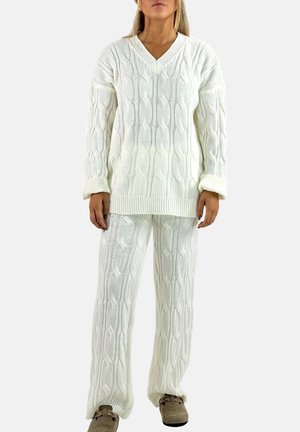 White knitted sweater and matching pants with cable pattern. Loose fit, wide sleeves, and ribbed cuffs. Material appears soft and textured.