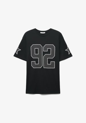Czarny bawełniany t-shirt z krótkimi rękawami, okrągłym dekoltem oraz białymi, siateczkowymi numerami "92" z gwiazdkowymi zdobieniami na rękawach.