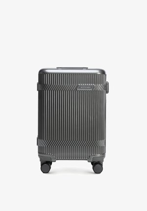 Grijze harde koffer met verticale ribbels, vier zwenkwielen en een "WITTCHEN" merklabel aan de voorkant.