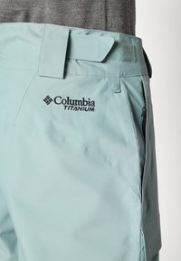 Șorturi Columbia Titanium de un teal deschis, cu o textură netedă, având talie cu Velcro, buzunare laterale cu fermoar și logo în față.