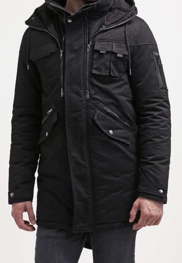 Svart parkasjacka tillverkad av texturerat tyg, med flera zip-fickor och knäppte fickor, en huva och en avslappnad passform.