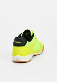 Baskets Kappa jaune vif et vert néon, vues de dos avec une bordure noire et une semelle blanche sur fond uni.