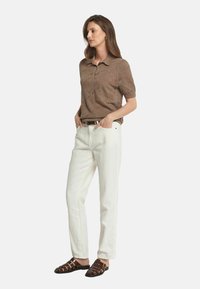 Brun mönstrad pikétröja, vita rakbenade jeans och bruna sandaletter med remmar. Tröjan har krage och korta ärmar.