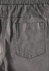 Grijze katoenen shorts met een elastische tailleband, een enkele achterzak en zichtbare stikseldetails. Gladde textuur met duurzaam materiaal.