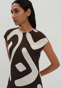 Braunes Kleid mit abstrakten weißen Mustern, kurzen Ärmeln, rundem Ausschnitt und glatter Textur, geeignet für die Freizeit oder Veranstaltungen.