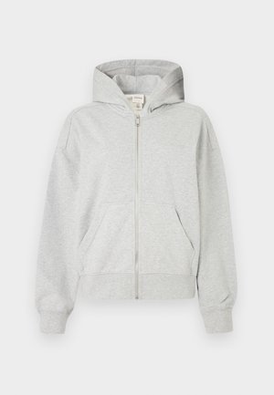 Siva zip-up dukserica s kapuljačom, dugim rukavima i prednjim džepovima. Izrađena od mekanog materijala s rebrastim manžetama i donjim rubom. Jednostavan dizajn, bez uzoraka.