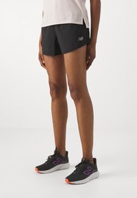 Black running shorts with a sleek design, lightweight material, and a silver logo. Black sneakers featuring purple accents and orange soles.