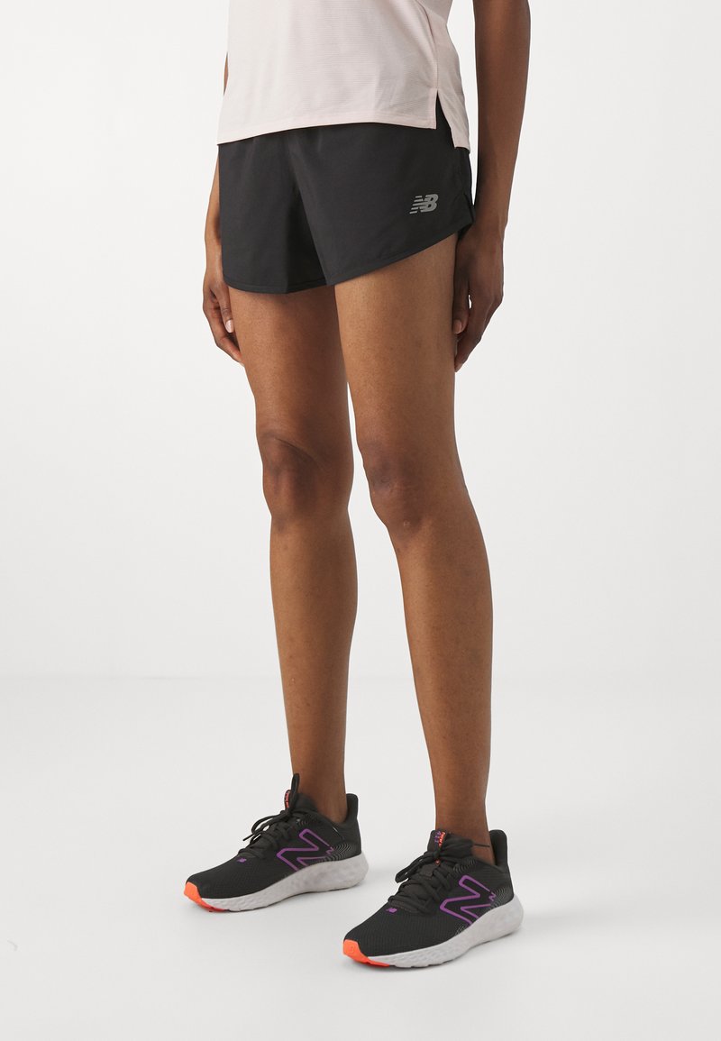 Black running shorts with a sleek design, lightweight material, and a silver logo. Black sneakers featuring purple accents and orange soles.