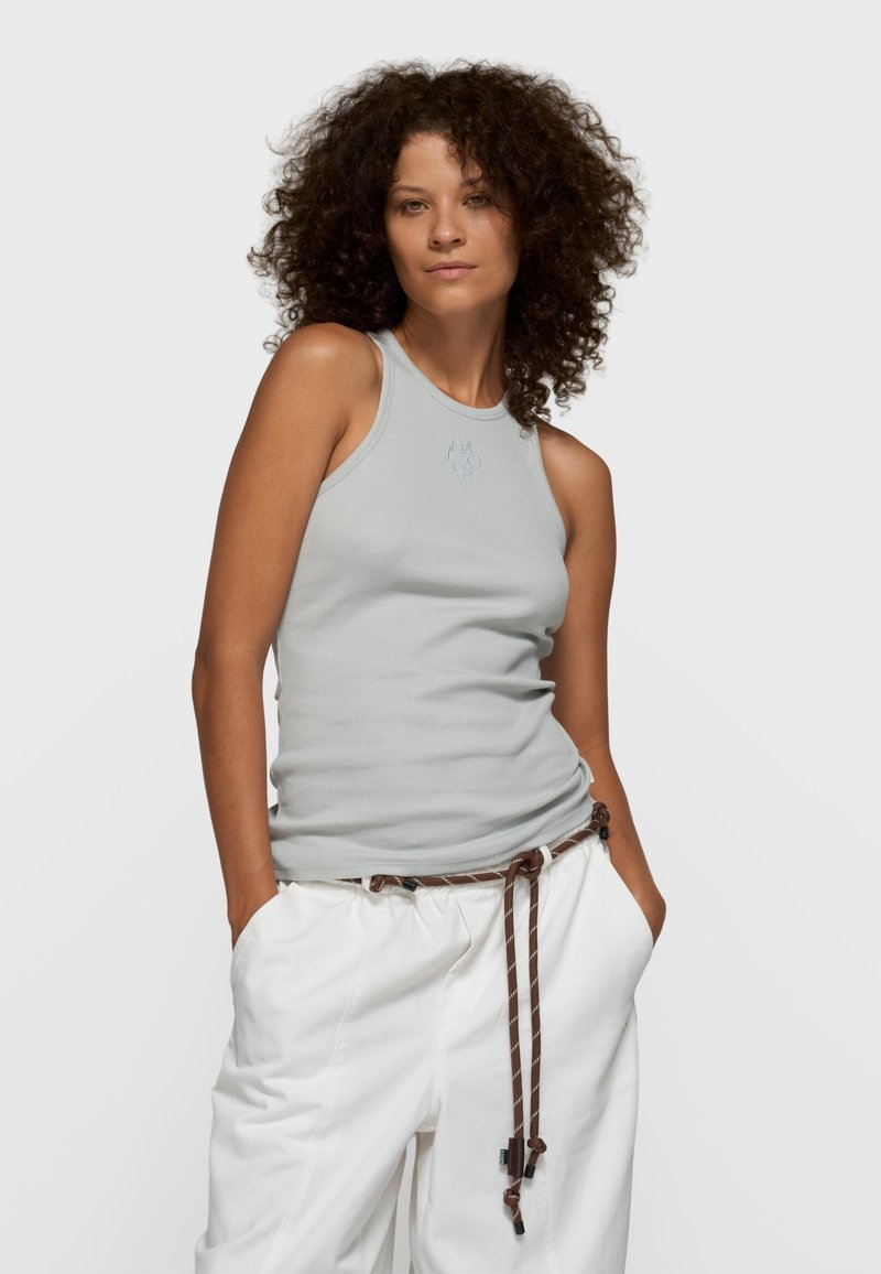 Top de tirantes gris claro con cuello redondo y un sutil logo bordado, combinado con pantalones blancos de cintura elástica con cordones marrones.