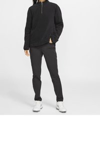 Black fleece pullover with a half-zip collar, paired with black tapered pants and white athletic shoes. Smooth texture and casual design.