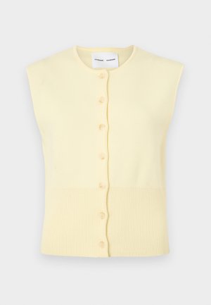 Gaiši dzeltens bezroku kardigans no mīksta dzijas materiāla. Ar pogu aizdari priekšpusē un ribota faktūra apakšā.