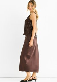 Brown sequined tank top paired with a dark brown satin maxi skirt, featuring a smooth texture and straight silhouette. Black pointed slingback shoes.