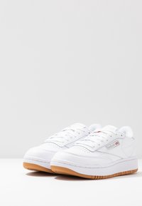 Vita lädersneakers med perforerade detaljer, platta snören, vadderad tungt och sula i gummirubber. Sidologotyp i grått.