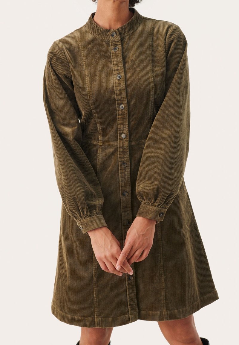 Robe en velours côtelé de couleur vert olive, dotée d'une patte de boutonnage à l'avant, de manches longues bouffantes, d'un col et d'un ourlet arrivant au genou avec une finition texturée.