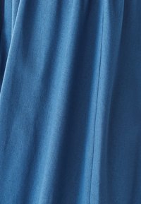 Modra tkanina z mehkim teksturo, z navpičnimi gubami in gladkim zaključkom. Minimalni vidni šivi izboljšujejo celoten videz.