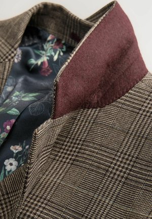 Braunes kariertes Blazer mit einem dunkelburgunderfarbenen Kragen. Gefüttert mit einem stoff mit Blumenmuster, das eine Mischung aus Farben und Texturen zeigt.