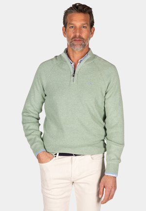 Lichtgroene pullover trui met een kwart-rits kraag, gebreide textuur, lange mouwen en een losse pasvorm, gedragen over een overhemd met kraag.