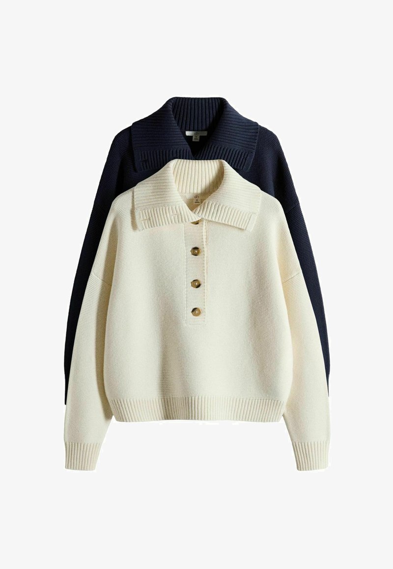 Jersey de punto crema con tres botones y cuello ancho superpuesto sobre un jersey de punto negro con un cuello de canalé ancho.