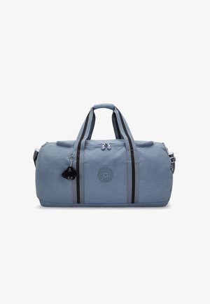Sac de sport bleu clair en tissu, avec deux bandes noires, logo rond, poignées supérieures et détail de pompon porte-clés amovible.