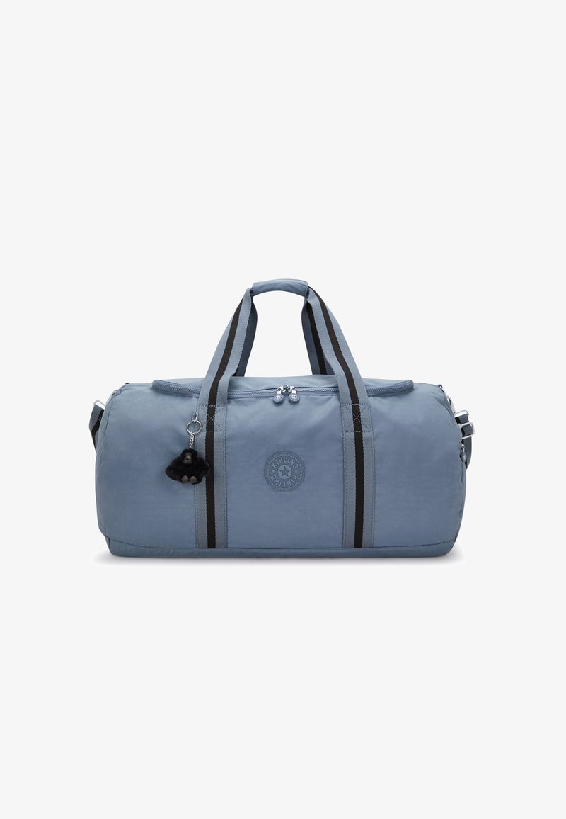 Vaaleansininen kangastyylinen duffel-laukku, jossa on kaksinkertaiset mustat raidat, pyöreä logo, yläkahvat ja irrotettava avaimenperi-pompom-yksityiskohta.