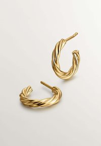 Pendientes de aro retorcidos en oro con una superficie suave y reflectante y un diseño ligeramente curvado. Presentan un cierre seguro con poste.