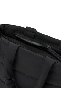 Svart vadderad tygväska med dubbla tygremmar, utrustad med en yttre dragkedjeficka och en slät innerfodring. Synliga sydda detaljer.