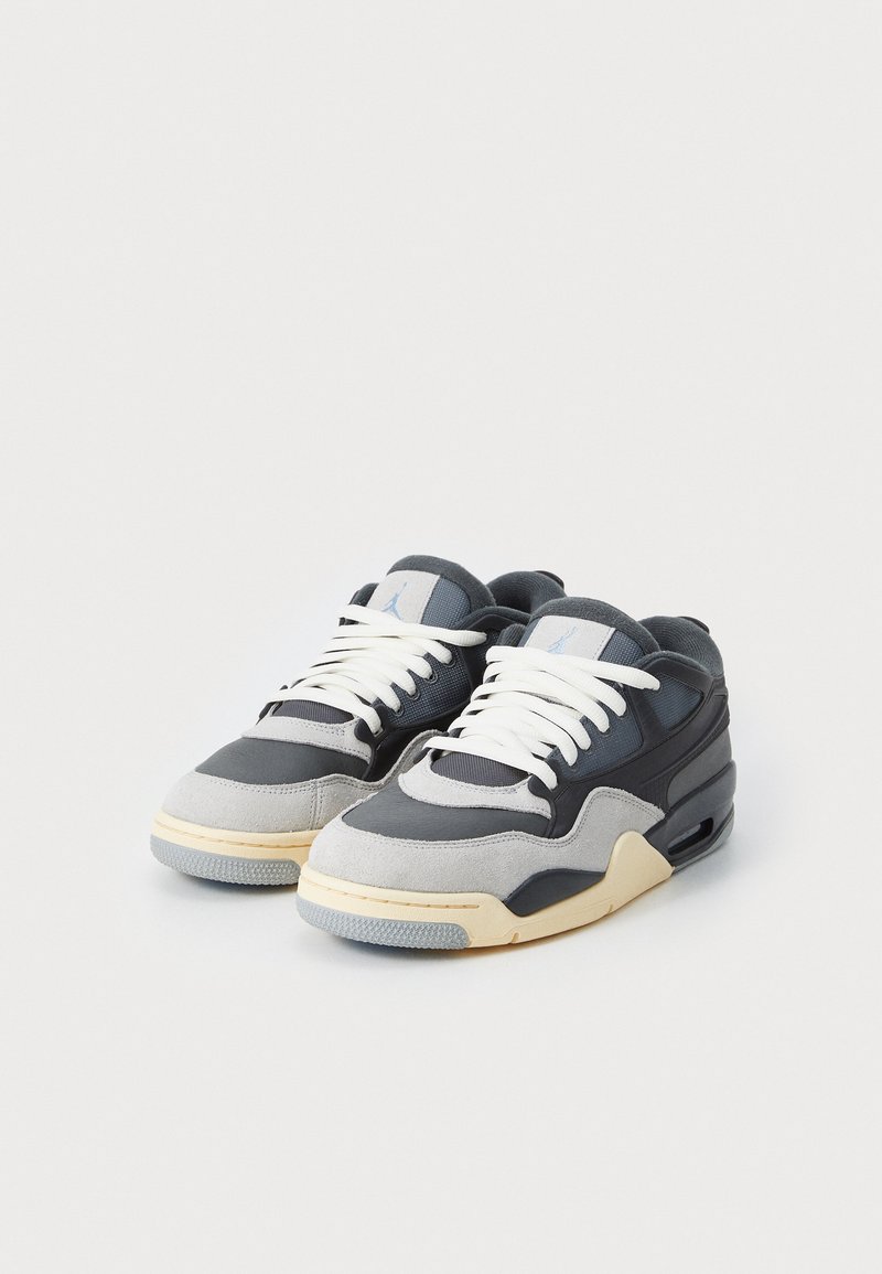 Sneaker grigi e neri realizzati in materiali scamosciati e in pelle, con lacci bianchi, suola beige e un'unità Air nel tallone per l'ammortizzazione.