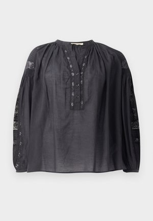 Svart bluse med høy krage, knappefront og lange ballongsleeves. Har gjennomsiktig mønstret stoff på skuldrene og mansjettene. Myk tekstur.