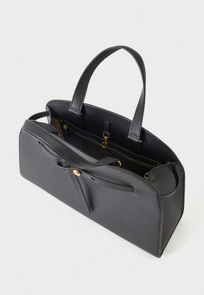Μαύρη δερμάτινη τσάντα με δύο χερούλια, ένα μπροστινό λουρί με χρυσό κουμπί και μια εσωτερική τσέπη με φερμουάρ.