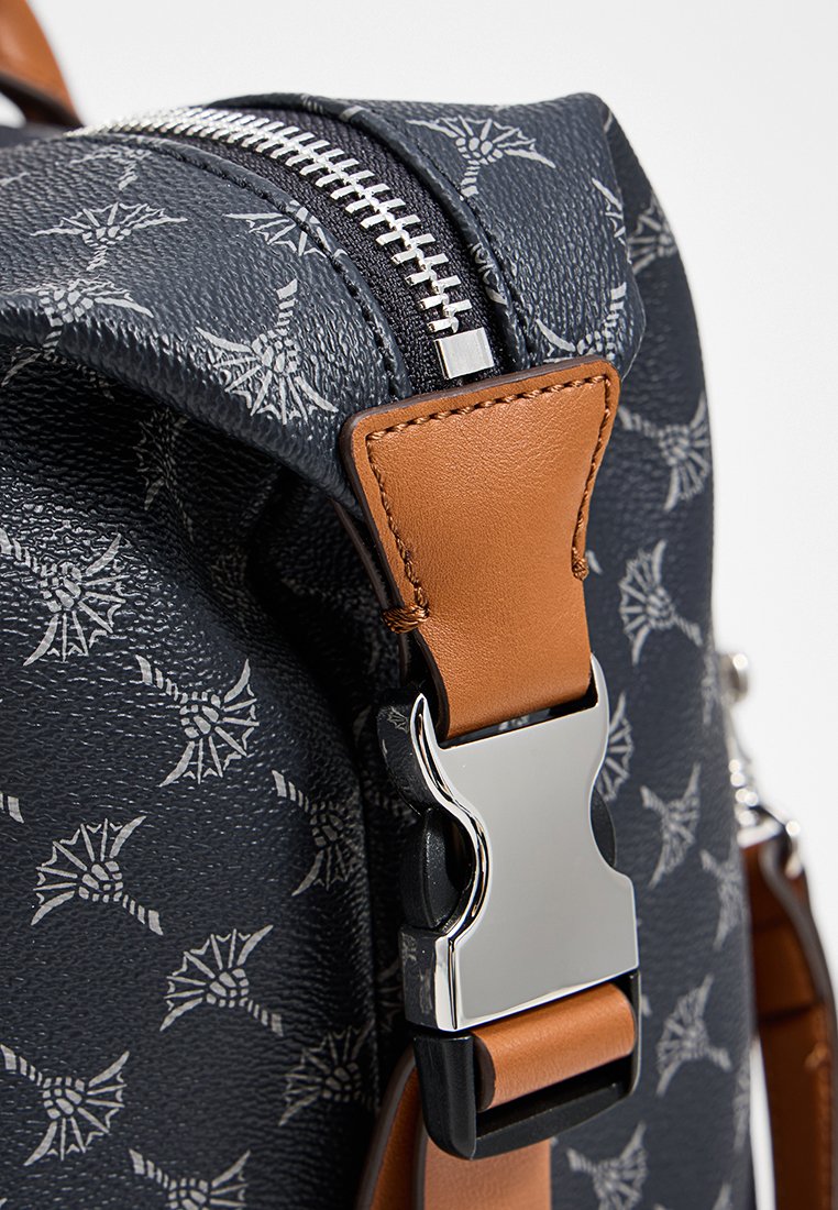 Dunkelblauer Rucksack mit strukturiertem Finish, ausgestattet mit einem silbernen Reißverschluss und akzenten aus hellbraunem Leder. Auffälliges Muster mit hellgrauen Motiven.