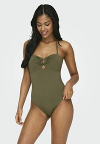 Traje de baño de una sola pieza en verde olivo con un corte en forma de llave en el busto, tirantes ajustables y tela suave y elástica. Diseño sencillo con un hardware mínimo.
