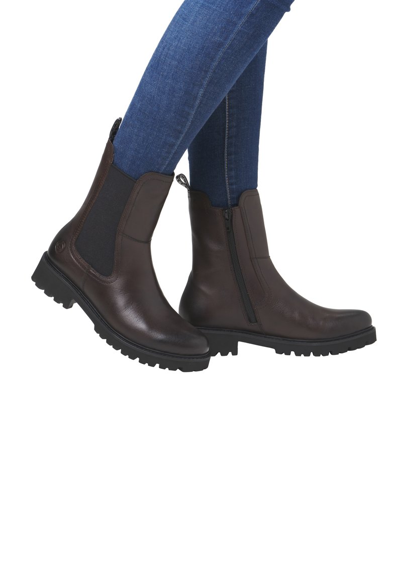 Brown leather Chelsea boots with side elastic panels and a zip, featuring a textured black rubber sole and a sleek, rounded toe design.