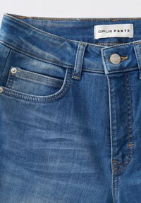 Pantaloni in denim blu chiaro con una texture liscia, dotati di chiusura con bottone frontale, passanti per cintura e design a cinque tasche con cuciture arancioni.