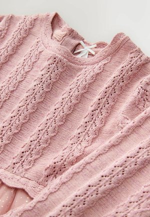 Stickad tröja i mjuk rosa med ett texturerat mönster som har upphöjda kabeldesigns och spetsliknande utskärningar; rundad halsringning och banddekoration.