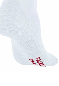 Biała skarpeta wyeksponowana pod kątem, z teksturowaną powierzchnią i czerwonym napisem po boku. Tło jest jednolite, białe.