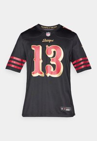 Μαύρη φανέλα NFL με χρυσούς αριθμούς "13" και κόκκινες ρίγες στα μανίκια. Το κείμενο "Faithful" πάνω από τον αριθμό, με μια ετικέτα επωνυμίας στο τελείωμα.